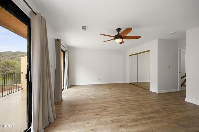 spare room featuring ceiling fan, visible vents, baseboards, and wood finished floors