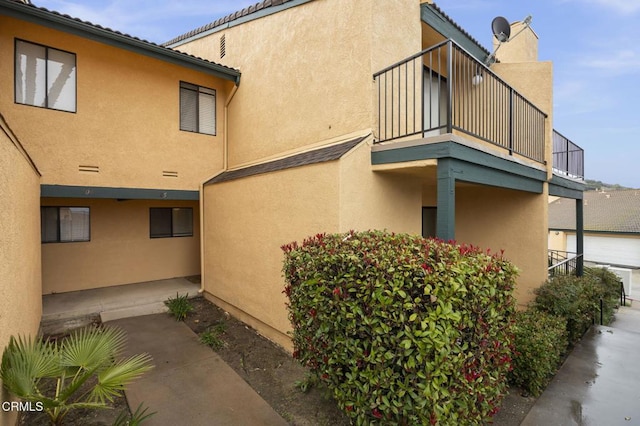 view of side of home with stucco siding and a balcony