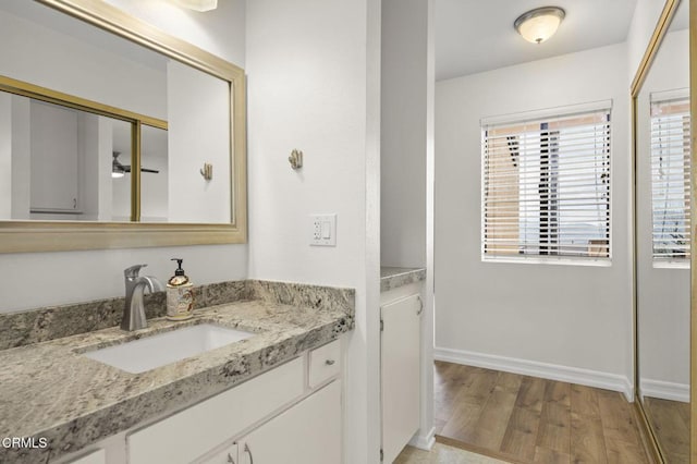 bathroom featuring baseboards, a ceiling fan, wood finished floors, and vanity