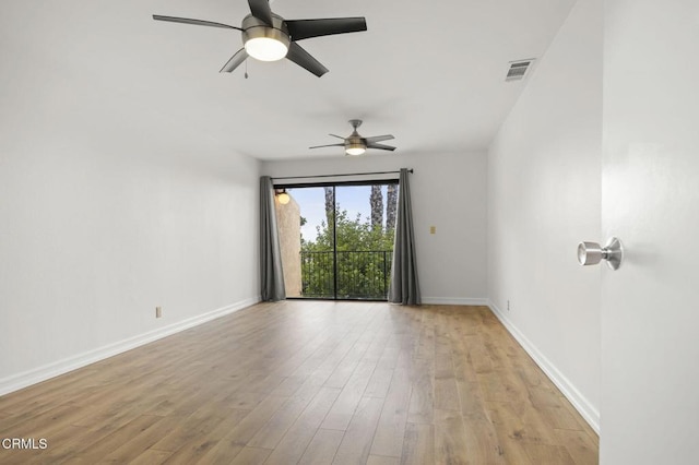 empty room with ceiling fan, visible vents, baseboards, and wood finished floors