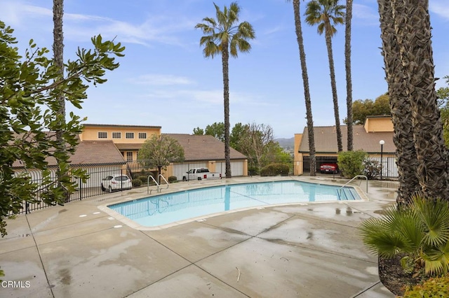 community pool with a patio area and fence