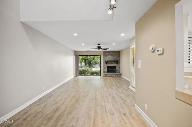 unfurnished living room featuring recessed lighting, baseboards, a stone fireplace, and light wood-style flooring