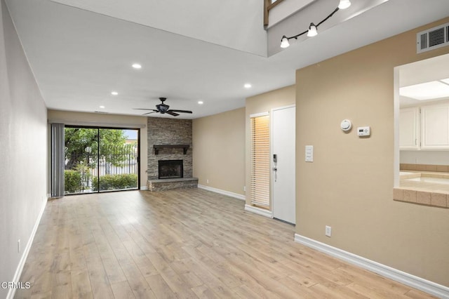 unfurnished living room with a stone fireplace, baseboards, visible vents, and light wood-type flooring