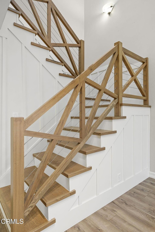 stairs featuring a decorative wall and wood finished floors