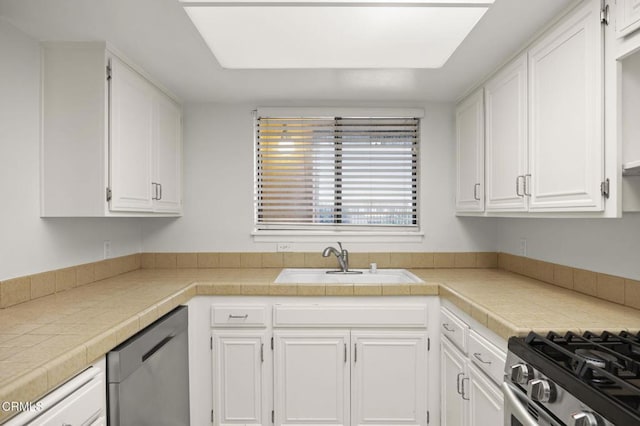 kitchen with white cabinets, appliances with stainless steel finishes, light countertops, and a sink