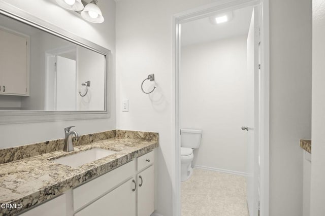 bathroom featuring baseboards, toilet, and vanity