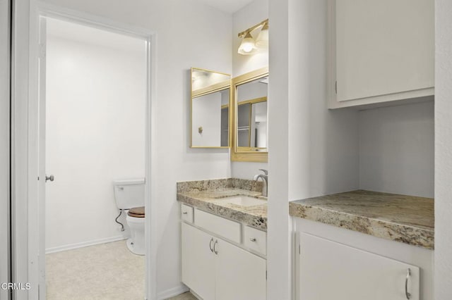 bathroom with vanity, toilet, and baseboards