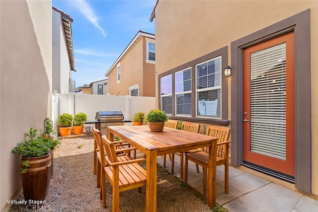 view of patio with outdoor dining space, grilling area, and fence