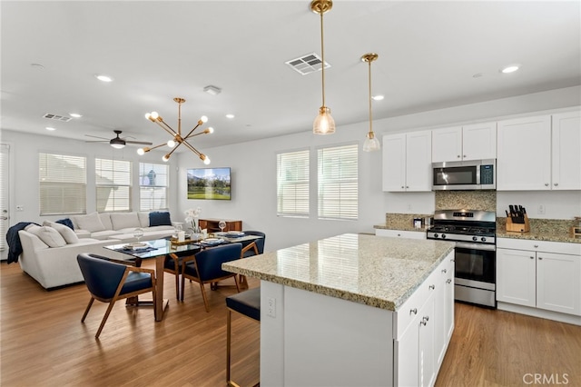 kitchen featuring visible vents, appliances with stainless steel finishes, a kitchen island, and wood finished floors