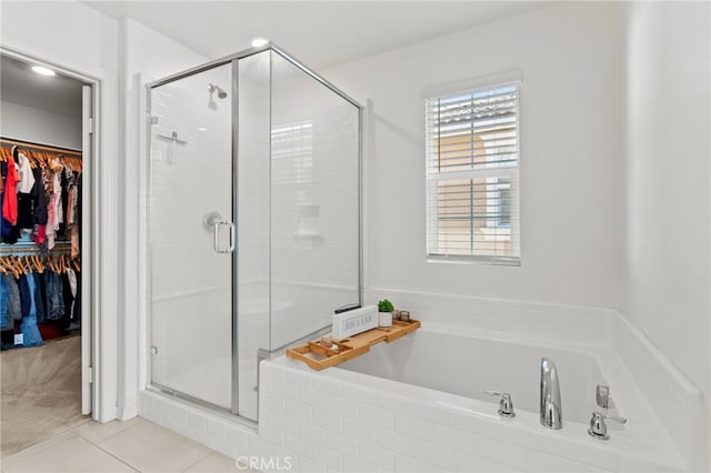 bathroom featuring a spacious closet, a bath, and a shower stall