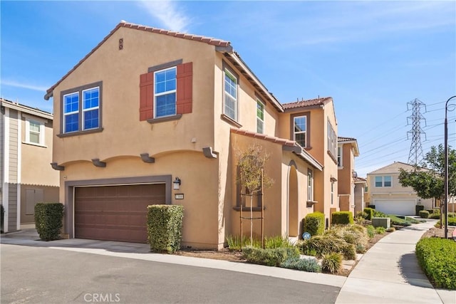 mediterranean / spanish house with a tiled roof, an attached garage, and stucco siding