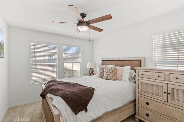 bedroom featuring baseboards, light colored carpet, and ceiling fan