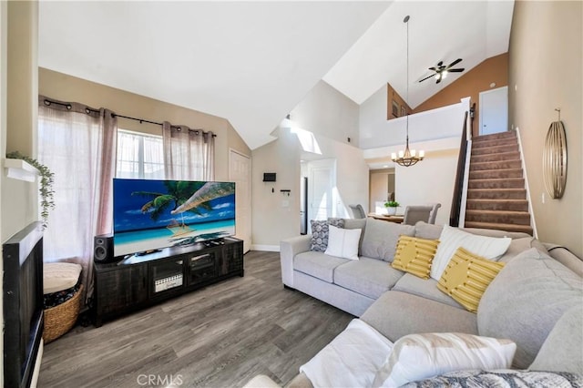 living room with ceiling fan with notable chandelier, stairway, wood finished floors, and high vaulted ceiling