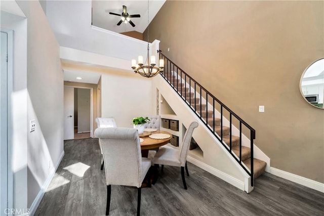 dining area with a towering ceiling, baseboards, wood finished floors, and stairs