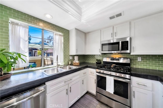 kitchen with tasteful backsplash, visible vents, white cabinets, stainless steel appliances, and a sink