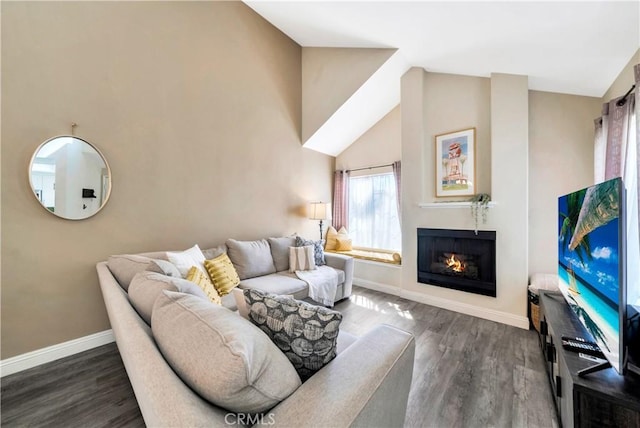 living area featuring a warm lit fireplace, high vaulted ceiling, baseboards, and wood finished floors