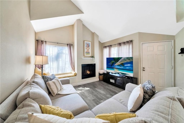 living area featuring a lit fireplace, baseboards, lofted ceiling, and wood finished floors