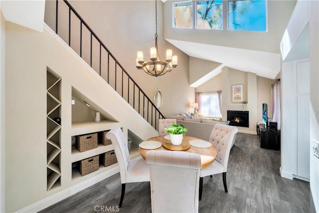 dining space featuring stairway, built in shelves, a warm lit fireplace, dark wood-type flooring, and a chandelier