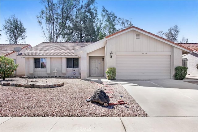 view of front of house featuring a tile roof, an attached garage, driveway, and stucco siding