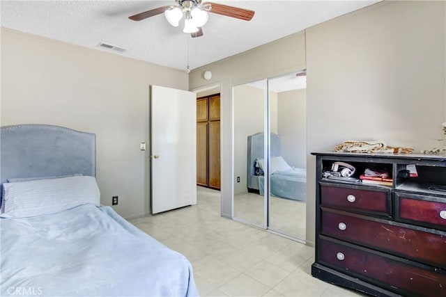 bedroom featuring a closet, a textured ceiling, visible vents, and a ceiling fan