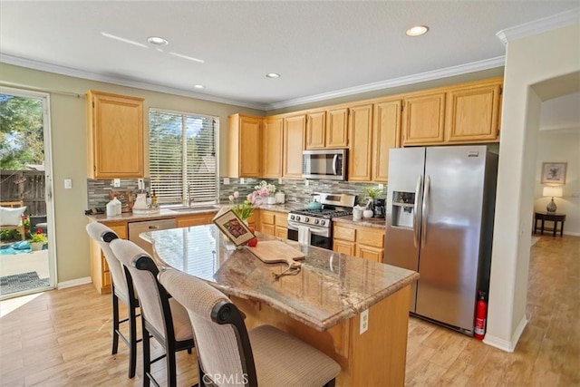 kitchen with light brown cabinets, light wood-style flooring, appliances with stainless steel finishes, and crown molding