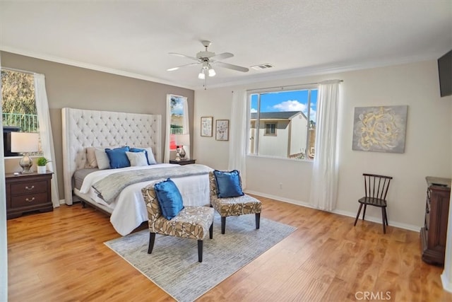 bedroom featuring baseboards, visible vents, light wood finished floors, ceiling fan, and crown molding