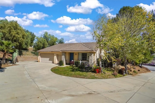 view of front facade with stucco siding, driveway, a garage, and fence