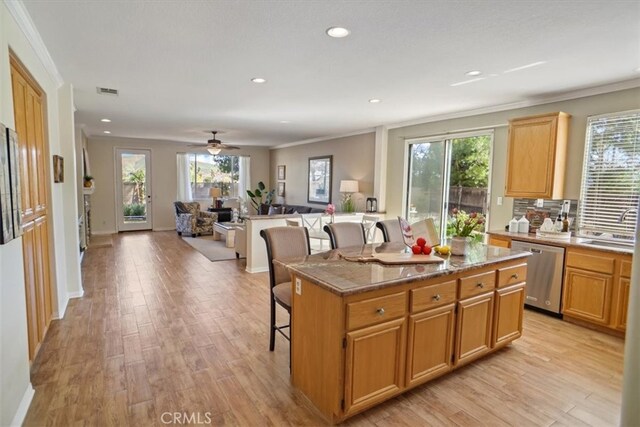 kitchen featuring stainless steel dishwasher, light wood-style flooring, a healthy amount of sunlight, and open floor plan