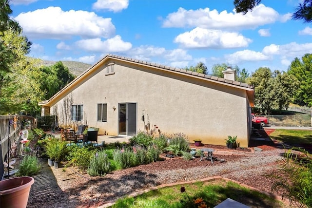 back of property with a patio, fence, a chimney, and stucco siding