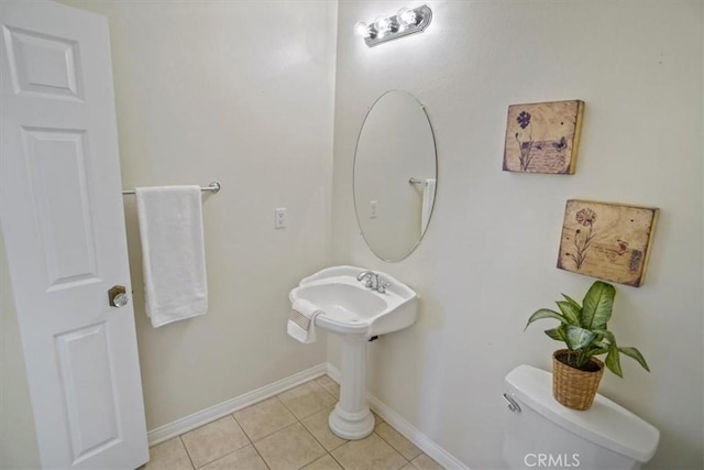 half bath featuring tile patterned floors, toilet, and baseboards