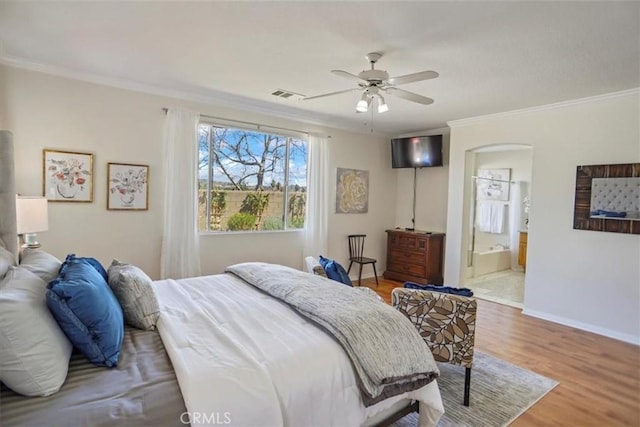 bedroom with visible vents, wood finished floors, arched walkways, crown molding, and baseboards