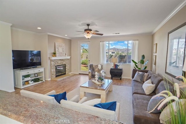 living room featuring visible vents, ornamental molding, a fireplace, and wood finished floors