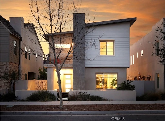 modern home with stucco siding, a fenced front yard, and a chimney