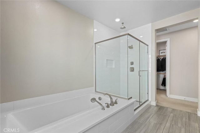 bathroom with visible vents, a shower stall, a walk in closet, baseboards, and a bath