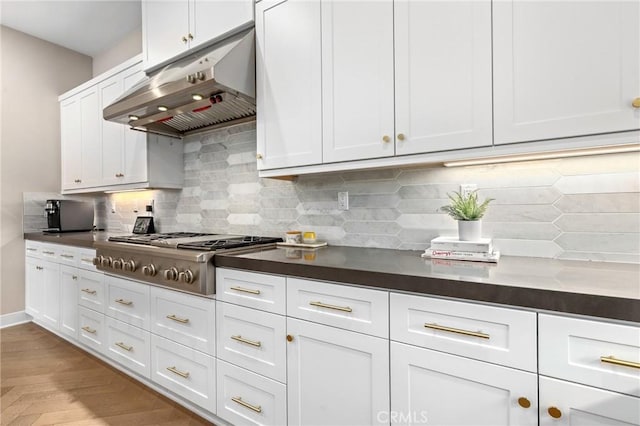 kitchen featuring under cabinet range hood, backsplash, white cabinets, and stainless steel gas cooktop