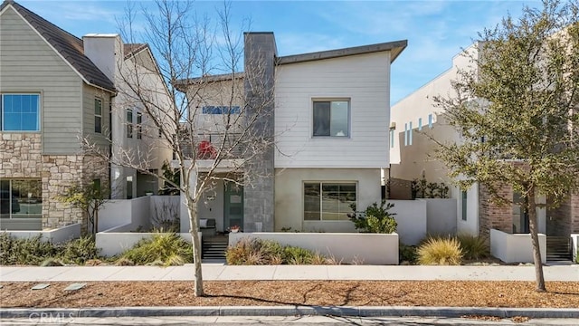 view of front of home featuring stucco siding, a fenced front yard, and a chimney