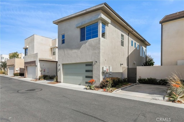 view of front of home featuring a gate, an attached garage, and stucco siding