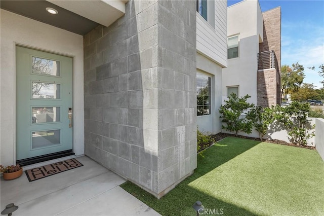 entrance to property featuring stucco siding and a lawn