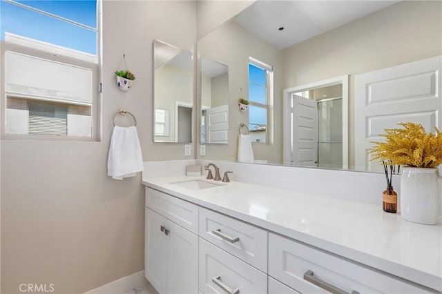 full bath featuring a shower with door, baseboards, and vanity