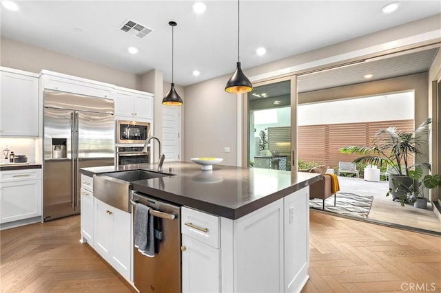 kitchen featuring white cabinetry, dark countertops, visible vents, and built in appliances