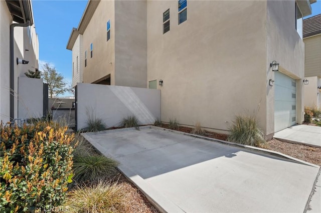 view of side of property featuring stucco siding and concrete driveway