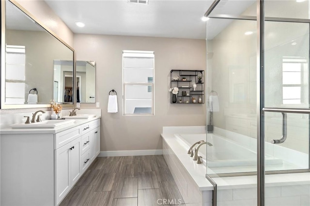 full bathroom featuring a sink, baseboards, a shower stall, and double vanity