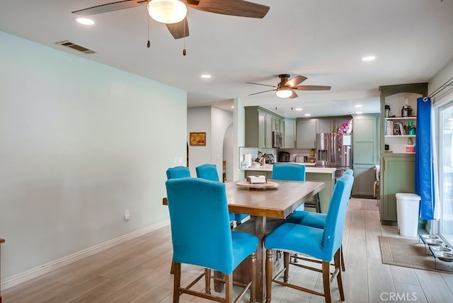 dining space featuring visible vents, light wood-style flooring, recessed lighting, arched walkways, and ceiling fan