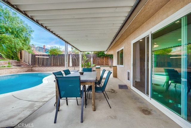 view of patio featuring outdoor dining space, a fenced backyard, and a fenced in pool