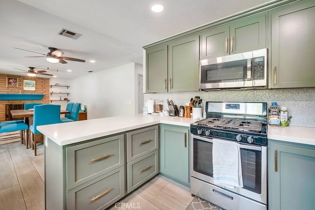 kitchen with visible vents, backsplash, stainless steel appliances, a peninsula, and green cabinets