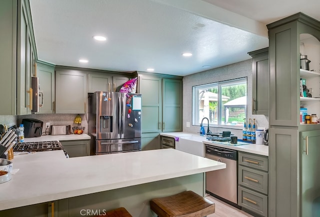 kitchen with a peninsula, light countertops, appliances with stainless steel finishes, and a sink