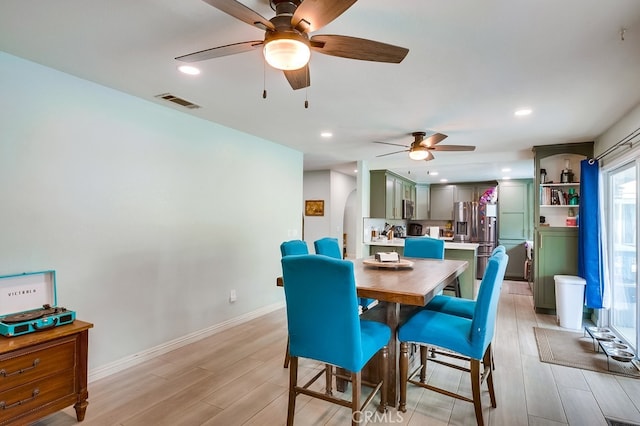 dining area featuring visible vents, recessed lighting, arched walkways, light wood-style floors, and baseboards