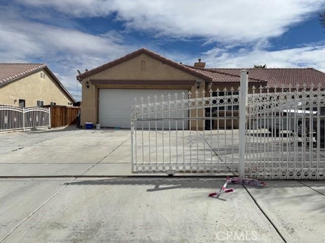 view of front facade with stucco siding, an attached garage, concrete driveway, and a gate