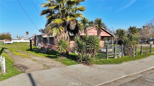 view of side of property with dirt driveway and fence