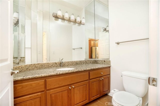 bathroom with toilet, vanity, and wood finished floors